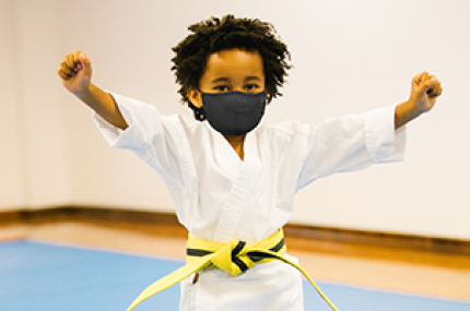 A boy in a mask in karate class at the YMCA