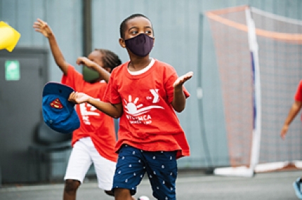 A boy in a mask running outside at YMCA Camp