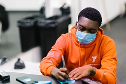 Teenage boy wearing a mask doing schoolwork