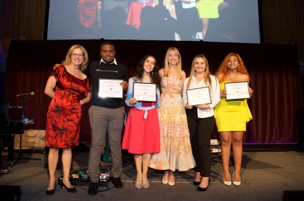6 people stand on a stage holding certificates