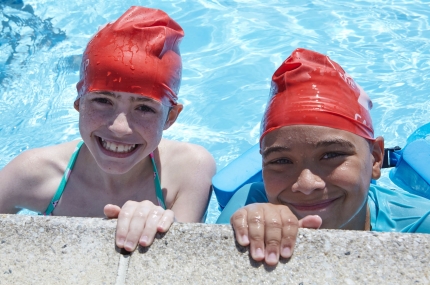 two kids smile in outdoor pool