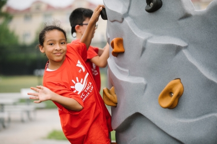 summer camp girl on climbing wall waving