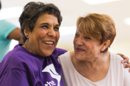Two older women embracing during a happy moment.