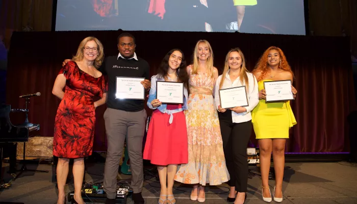 6 people stand on a stage holding certificates