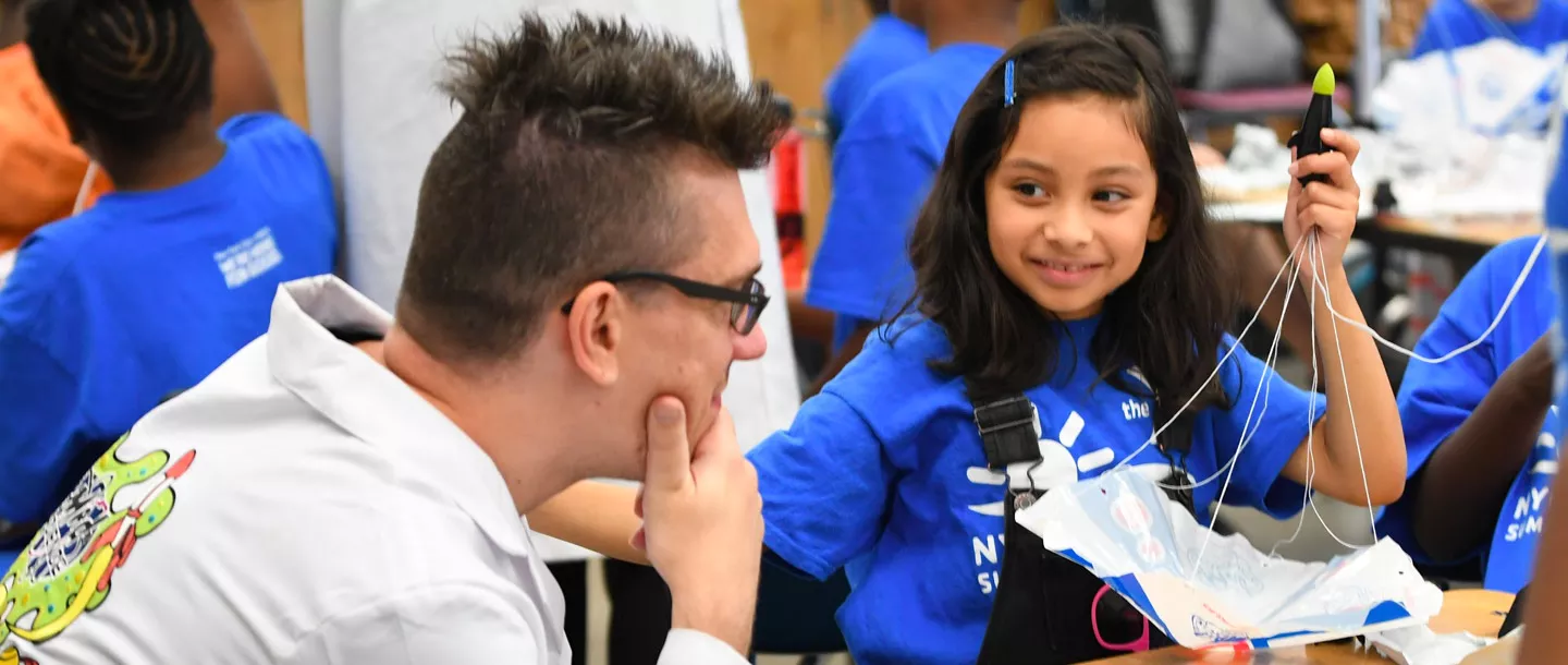 A girl shows a camp instructor her science project at the Dodge YMCA summer day camp.