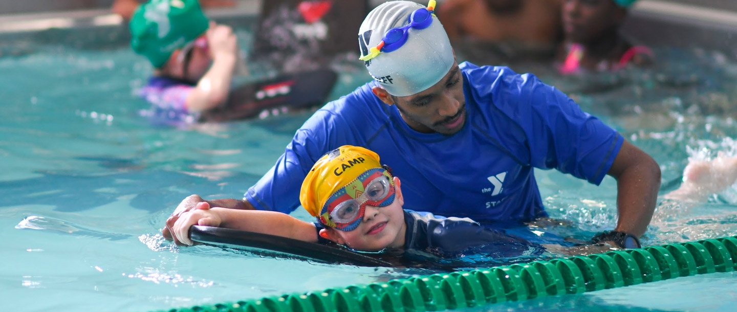 A camp counselor helps a child learn to swim at the Harlem YMCA summer day camp.