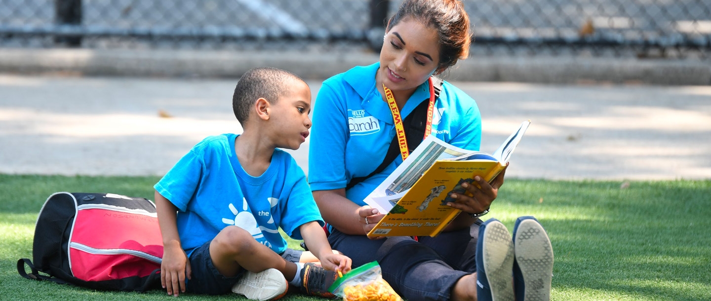 A counselor reads to a camper at the North Brooklyn YMCA summer day camp.