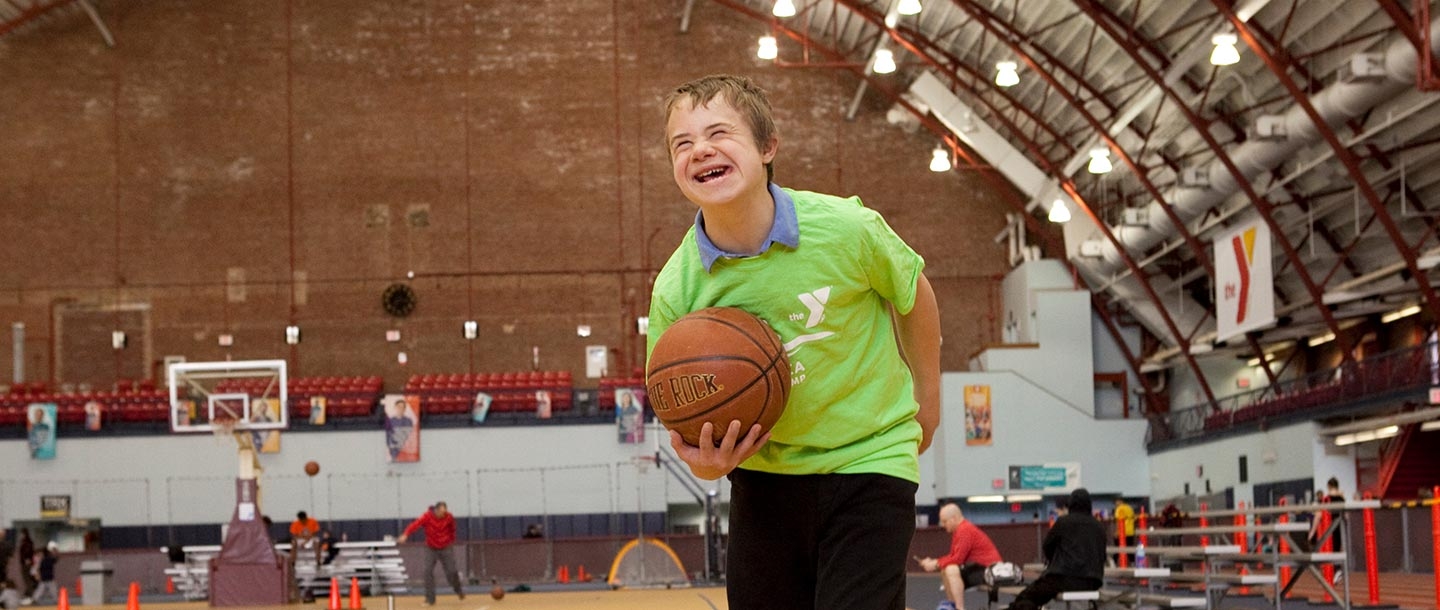 Boy with basketball smiling at Park Slope Armory YMCA in Brooklyn