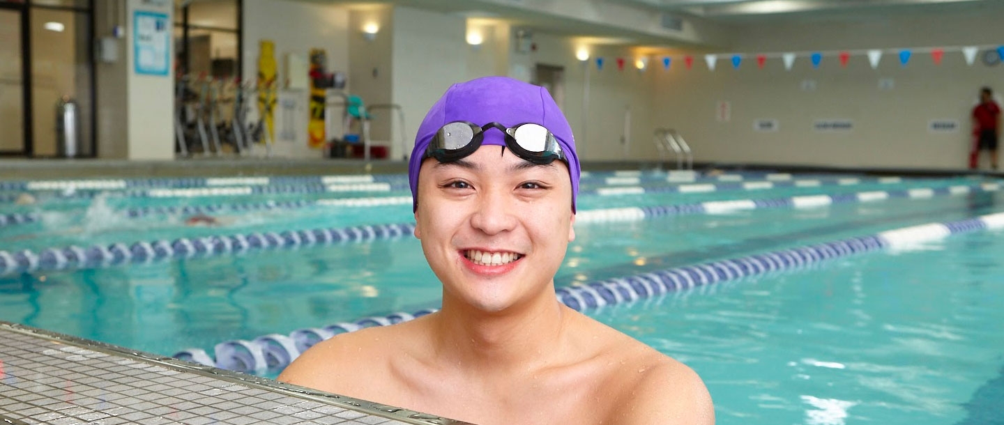 Man smiling at end of lap lane of Vanderbilt YMCA indoor pool