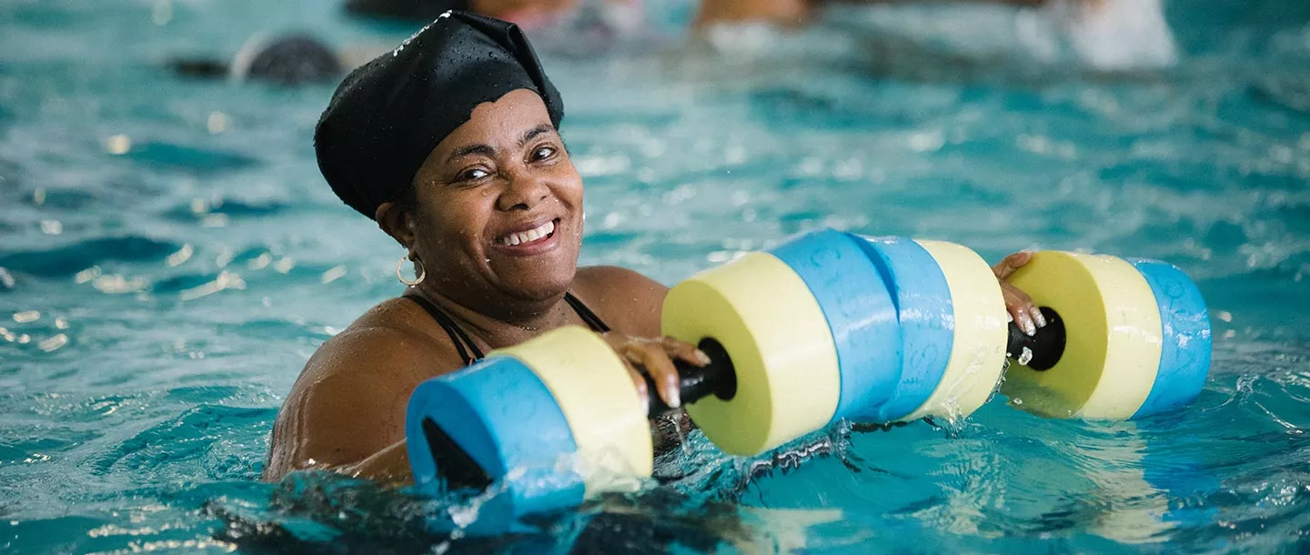 Woman with foam water weights during aqua aerobics class at Bronx YMCA indoor pool