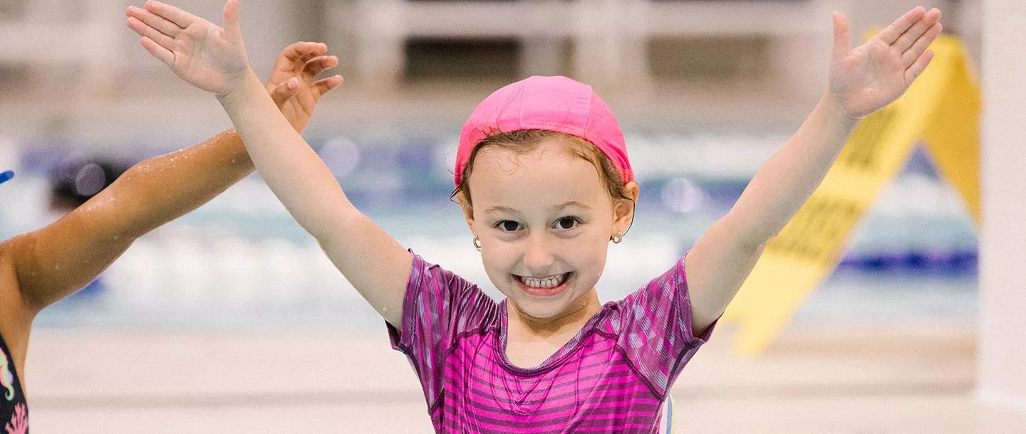 Girl with pink swim cap and arms in Y
