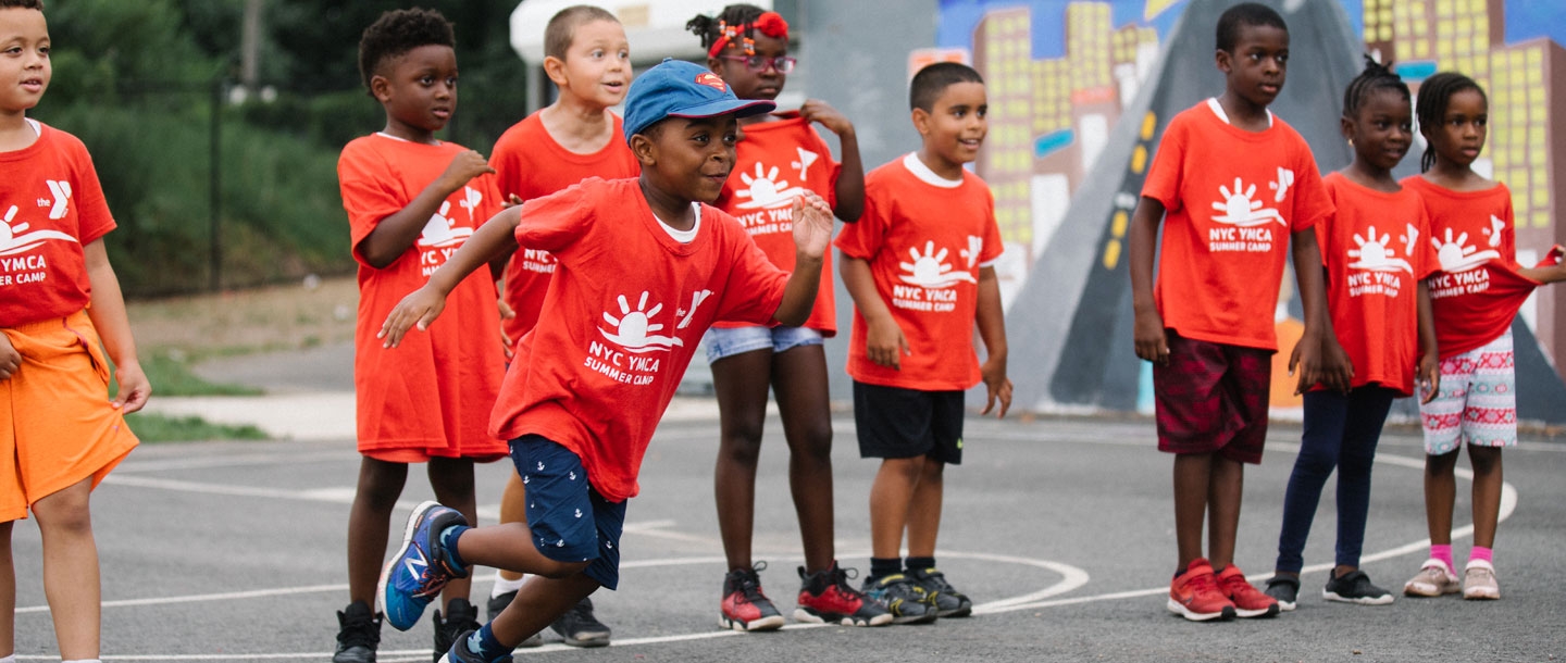 A young boy runs in front of a group of kids at the Bronx YMCA Summer Inclusion Camp.