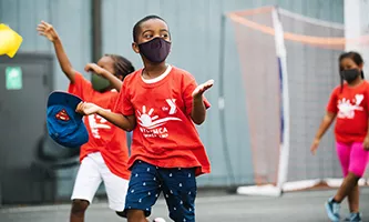 A boy in a mask running outside at YMCA Camp
