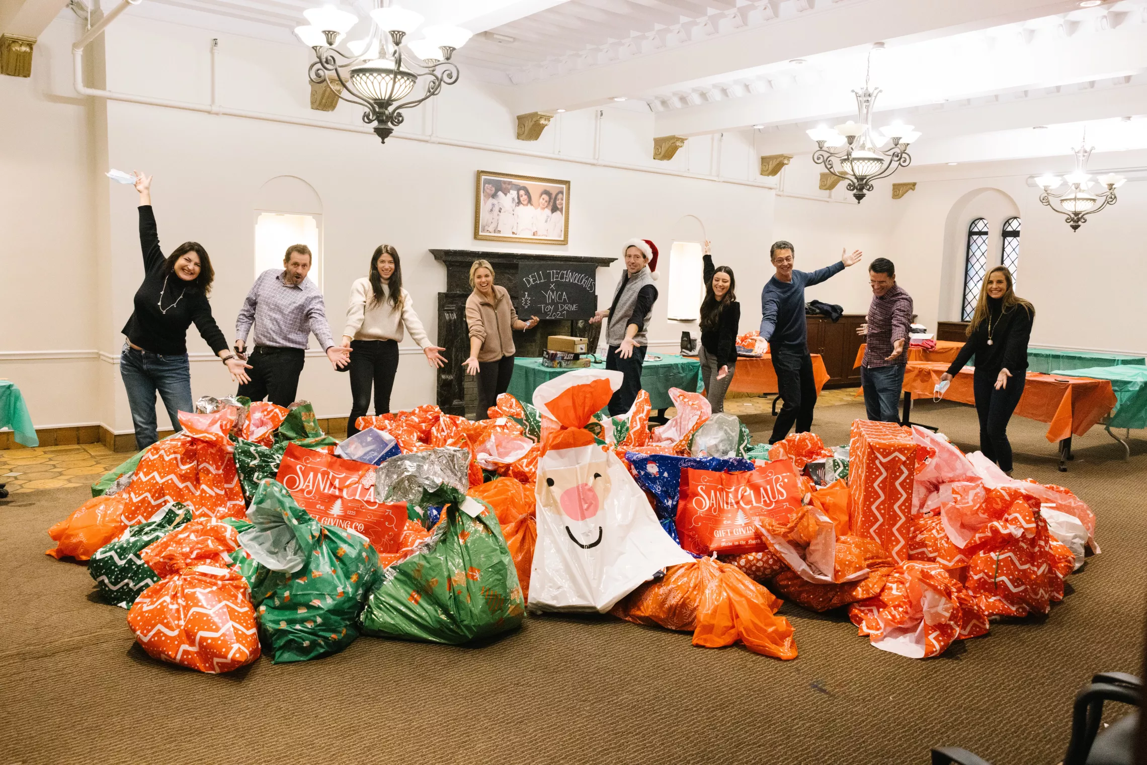 A group of individuals posing behind a bunch of wrapped gifts