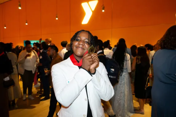 Teen holds up medal for volunteer of the year at Y Champions event.