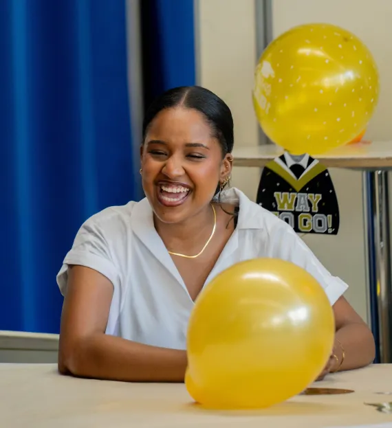 Teen smiles big at College Decision Day among balloons
