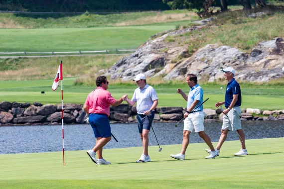Kris Magel (committee co-chair) and golfers fist bumping on golf course at 2026 Golf & Gala