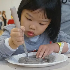 Young girl sculpts clay for art project