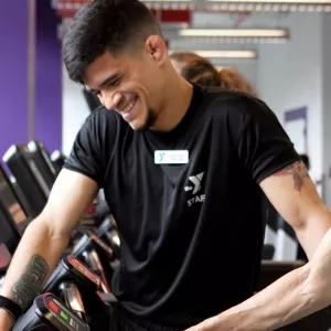 A personal trainer works with a YMCA member on a treadmill.