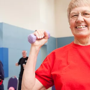 A senior lifts hand weights in a YMCA senior fitness class.