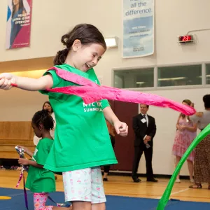 A child at a YMCA day camp twirls in the gym.