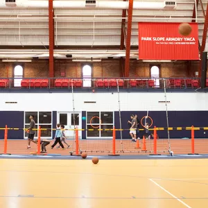 Family playing basketball at the Park Slope Armory YMCA indoor gymnasium
