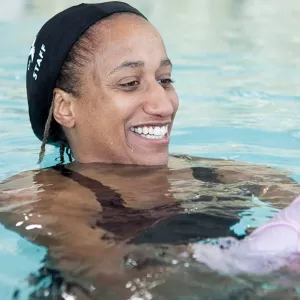 Private lesson instructor teaching young girl to swim in pool at YMCA