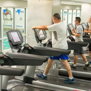 Chinatown YMCA members work out on treadmills, overlooking an indoor pool.