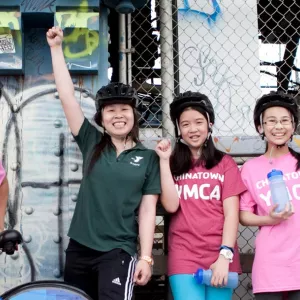 Five girls in YMCA tee shirts raise their fists and smile.