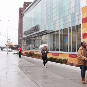 People walk past the new Coney Island YMCA on the sidewalk.