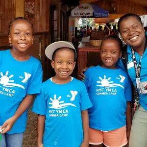 Three kids and a YMCA staff member at a YMCA summer day camp.