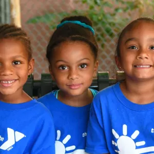 Five preschool girls sitting on bench outside at Dodge YMCA camp in Brooklyn