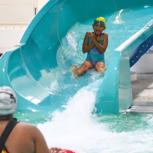 Summer camper sliding down Rockaway YMCA indoor water slide in Queens