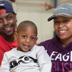 Family of dad, son, and mom together at YMCA basketball court 