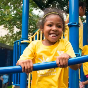 Girl playing on outdoor playground in Brooklyn during YMCA summer camp