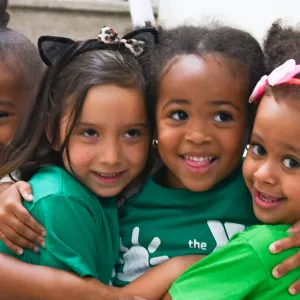 Four girls hug in hallway of Harlem YMCA during summer camp