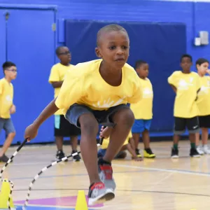 Boy jumping rope in Jamaica YMCA indoor gymnasium during summer camp