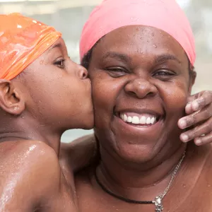 A mother and her child swim in a YMCA pool.