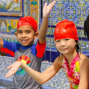 Group of kids swimming at YMCA indoor pool during summer camp