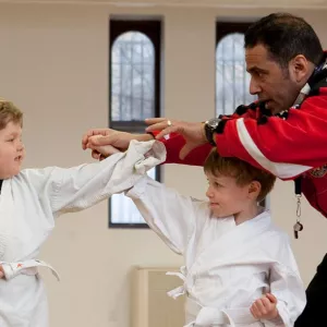 Two kids learning karate pose with instructor