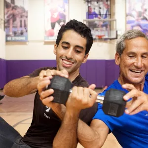 Two men passing weight to each other at Brooklyn YMCA group fitness class