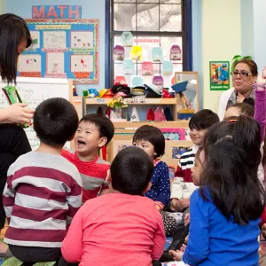 Teacher reading story to preschoolers sitting on classroom floor at YMCA UPK class in Queens