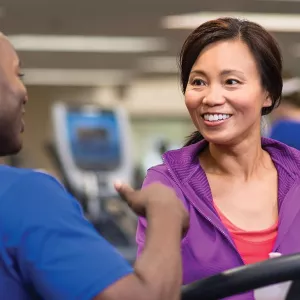 YUSA personal trainer talks to woman walking on treadmill