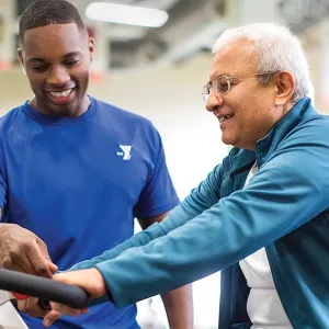 YUSA personal trainer showing client how to ride a bike