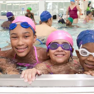 Four girls swimming at YMCA indoor pool in Brooklyn