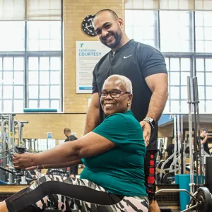 Woman working out in weight room of West Side YMCA with personal trainer
