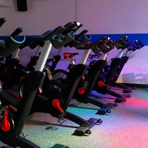 Spin bikes in North Brooklyn YMCA indoor cycling studio with black light