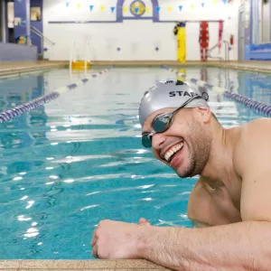 YMCA staff smiling as he starts to swim at North Brooklyn YMCA indoor pool