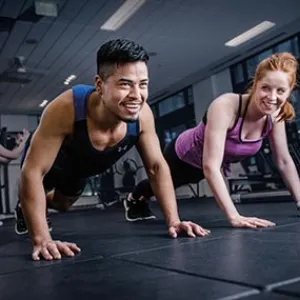 Man and woman doing plank push ups on mat at YMCA strength training studio in gym