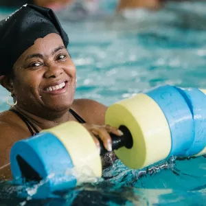 Woman with foam water weights during aqua aerobics class at Bronx YMCA indoor pool